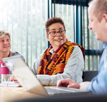 Three people sat at a desk with laptops